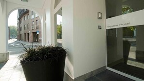 The entrance to Square Hotel with a potted plant in the foreground and a view of the street and buildings in the background. - Square Hotel (Kortrijk)