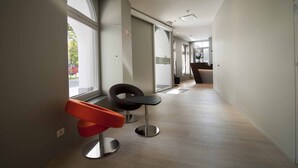 A modern hallway with two chairs, large windows, and a door leading to another room. - Square Hotel (Kortrijk)