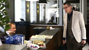 A hotel reception area with a modern design, featuring a reception desk, black pendant lights, and a visible bar area in the background. - Square Hotel (Kortrijk)