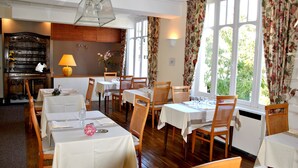 A dining area with multiple tables and chairs, a piano, and a large window with curtains. - Hermitage (Perros-Guirec)