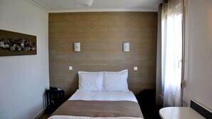 A hotel room with a wooden headboard, a bed with white bedding, a bedside table, and a window with curtains. - Hermitage (Perros-Guirec)