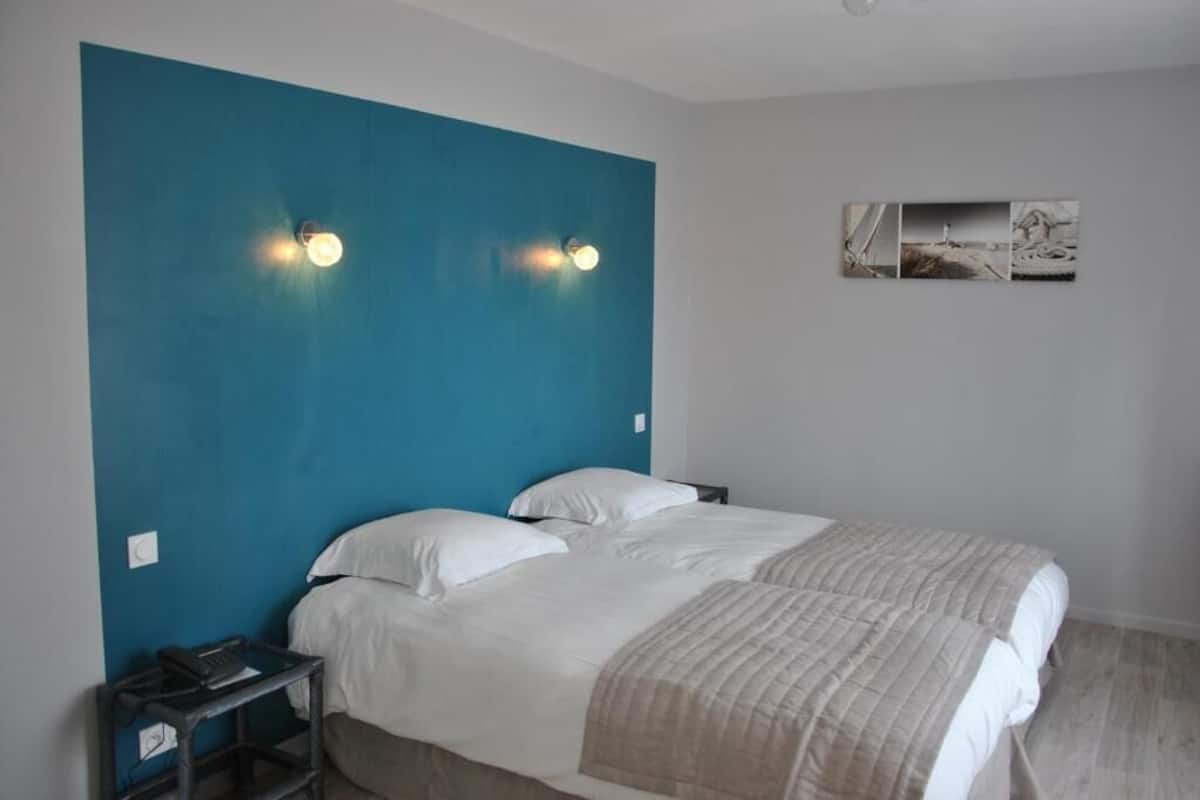 Ein Schlafzimmer mit einem großen Bett, zwei Nachttischen, einer blauen Akzentwand und Wandleuchten.