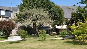 A residential garden with a white bench, a stone wall, and a variety of flowering shrubs. - Hermitage (Perros-Guirec)