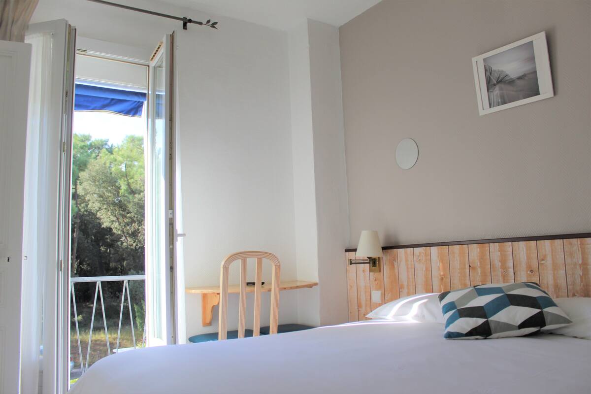 Ein Schlafzimmer mit einem Bett, einem Sessel, einem Fenster und einer Wandlampe.