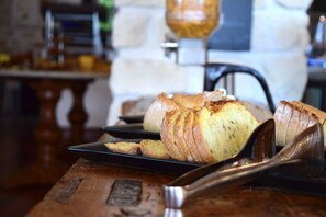 A loaf of bread on a wooden table with a metal serving spoon beside it. - Hotel Mer et Forêt (Saint-Trojan-les-Bains)