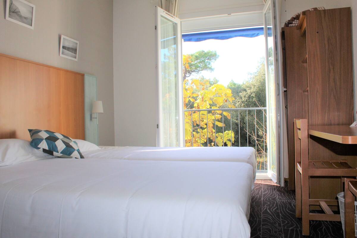 Ein Hotelzimmer mit Bett, Schreibtisch und einem Balkon mit Herbstlaub.