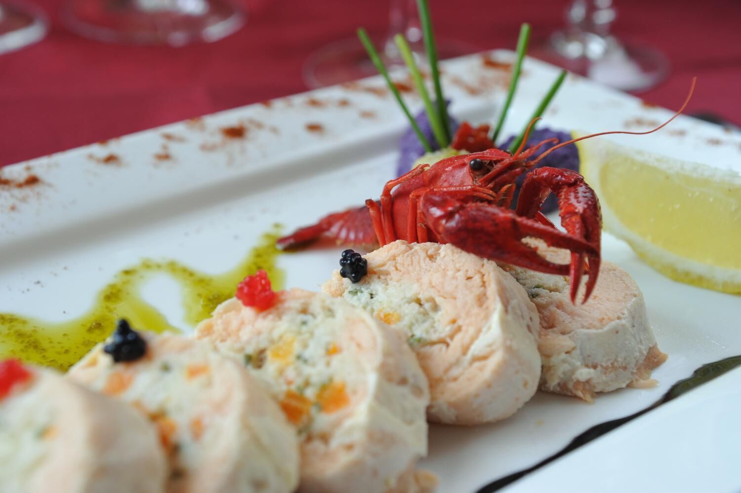 A seafood dish with lobster and a lemon wedge on a white plate.
