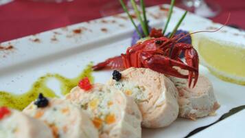 A seafood dish with lobster and a lemon wedge on a white plate.