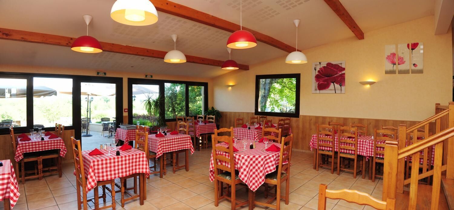 A restaurant with red and white checkered tablecloths, wooden chairs, and pendant lighting.