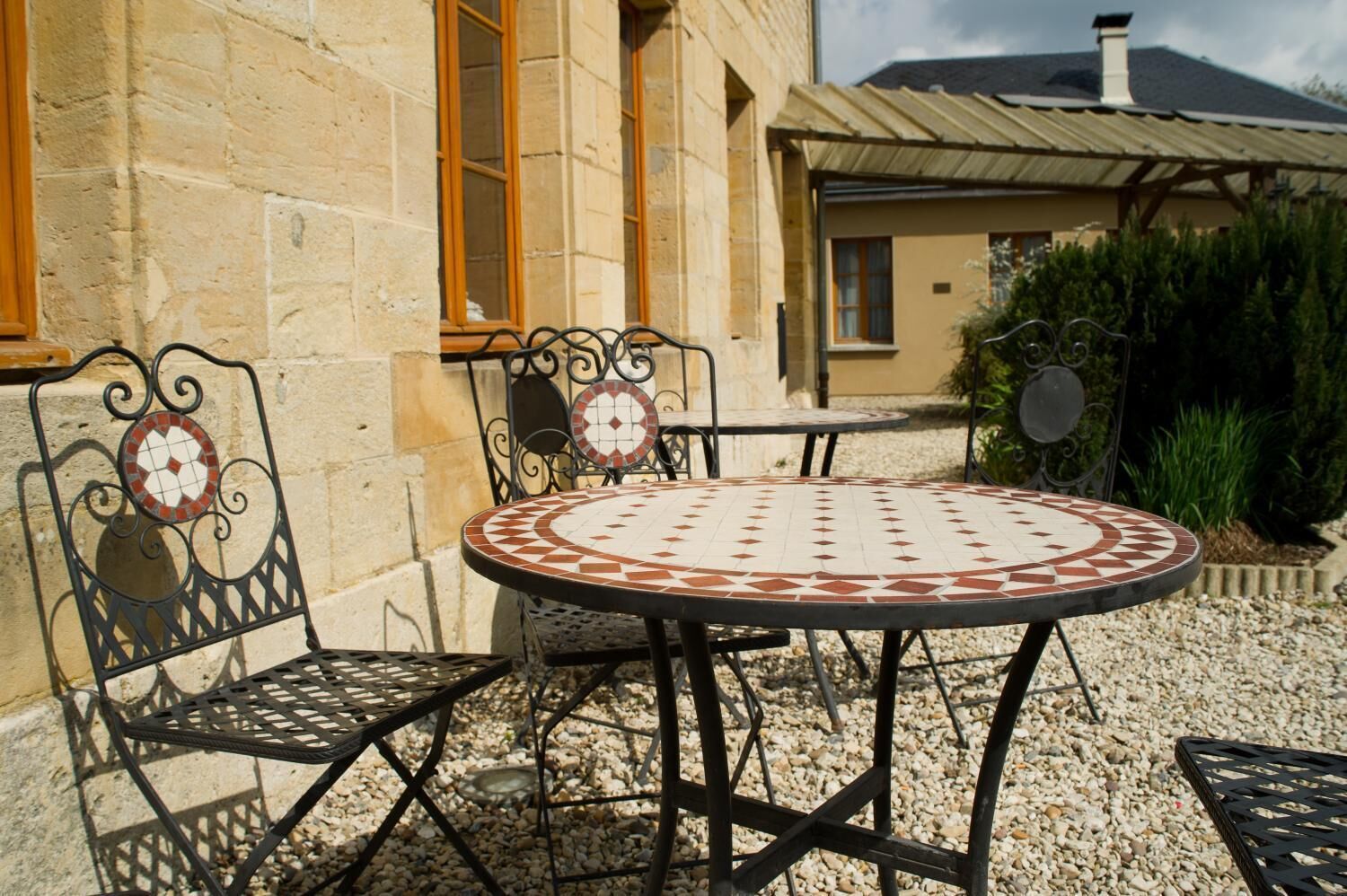 Un patio con un tavolo rotondo e quattro sedie, circondato da un muro in pietra e un edificio con tetto in tegole.