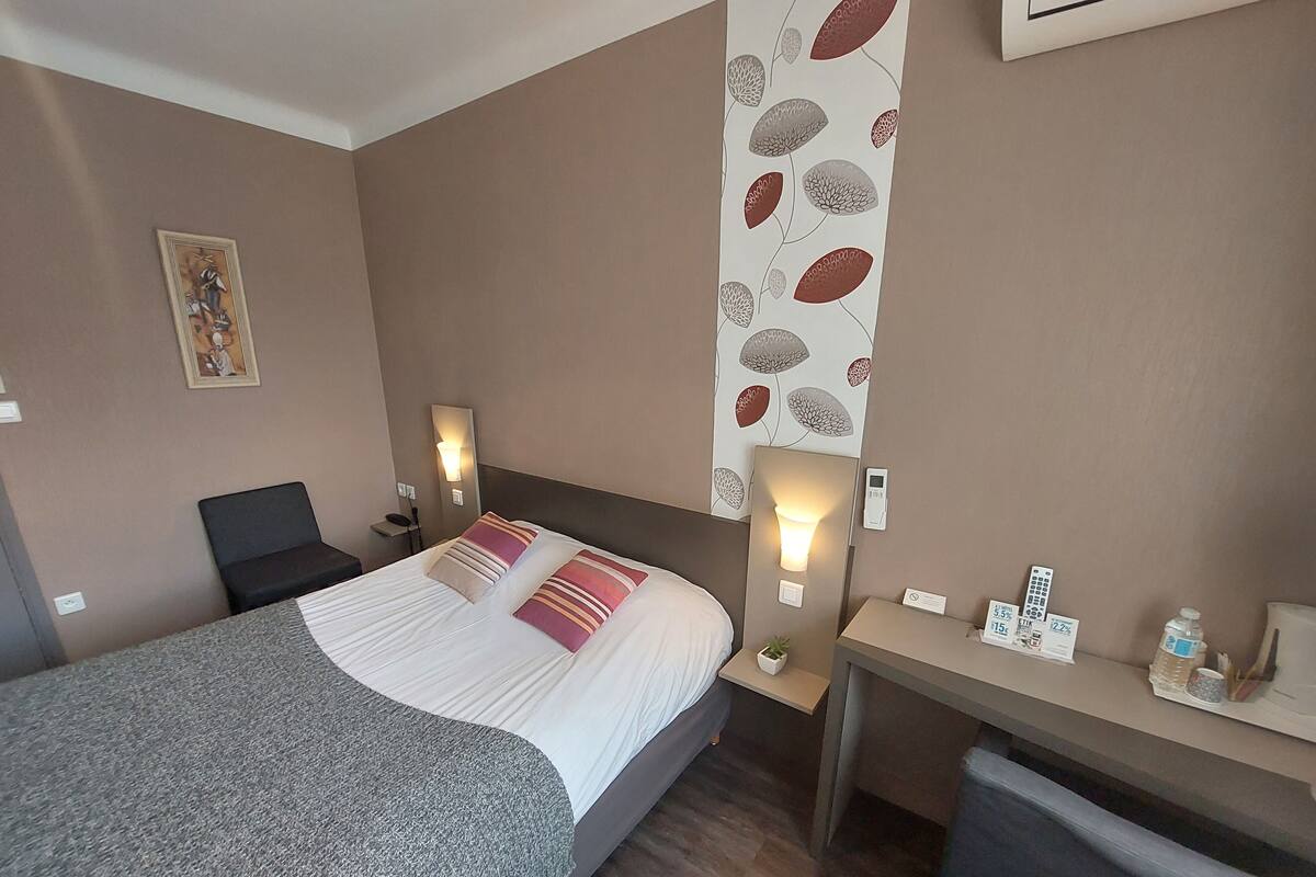 Una habitación de hotel con cama, mesitas de noche, escritorio y una silla.