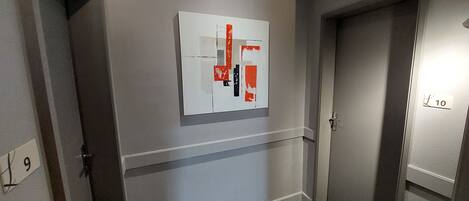 Un pasillo con una puerta marcada '10', una obra de arte en la pared y un timbre.