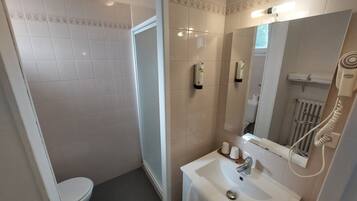Une salle de bain équipée de toilettes, d’un lavabo, d’un miroir et d’un sèche-mains.