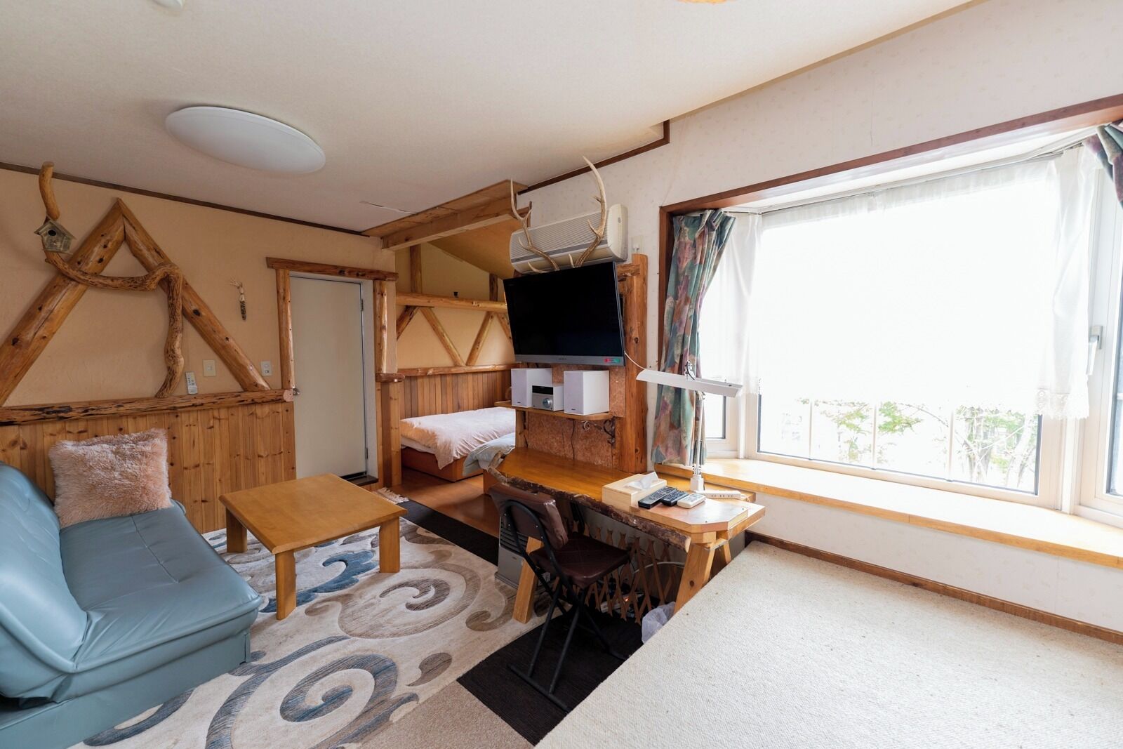 A cozy room with a sofa, a small table, a TV, and a window with curtains.