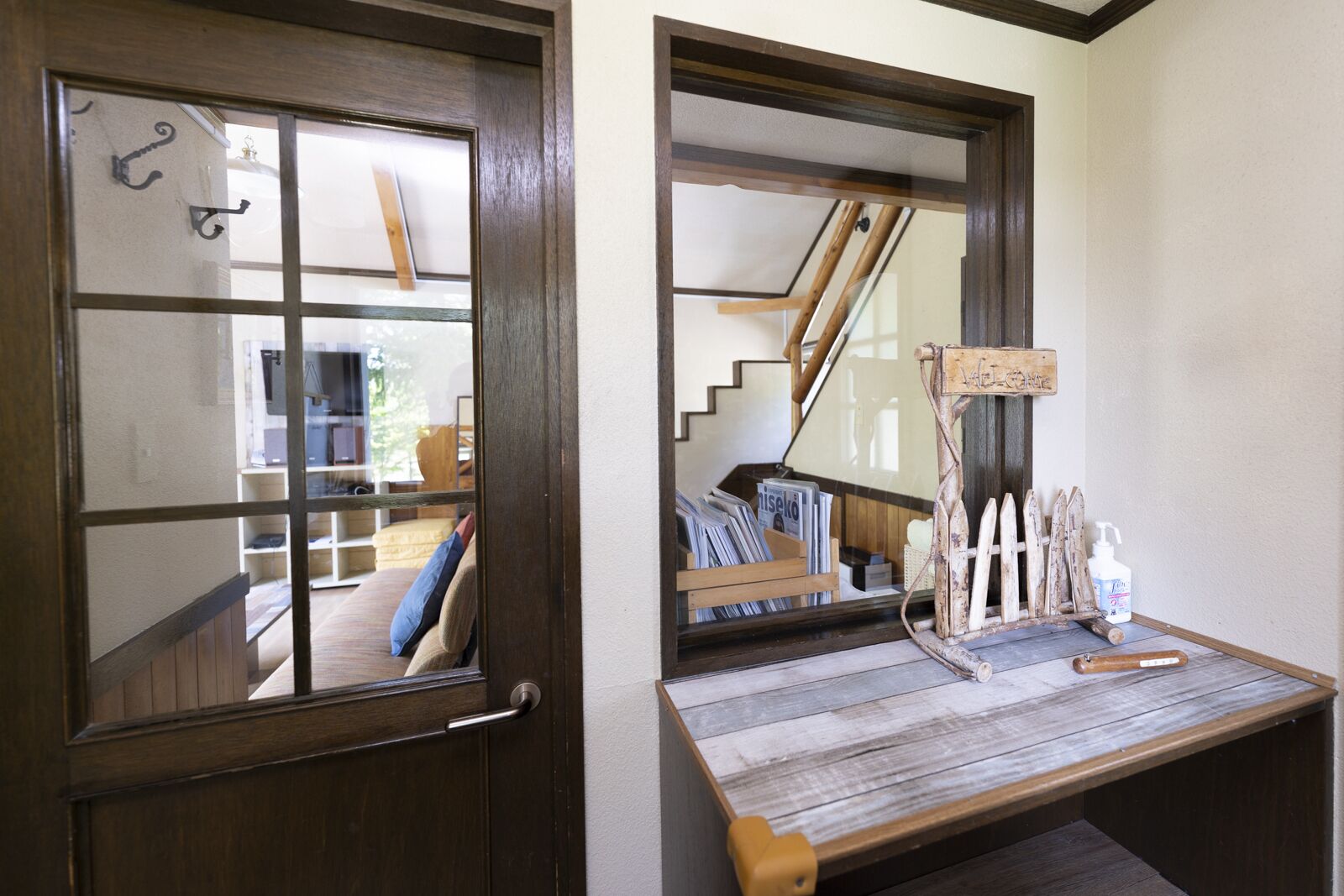 A wooden door with a glass panel, a small wooden table with a sign, and a staircase in the background.