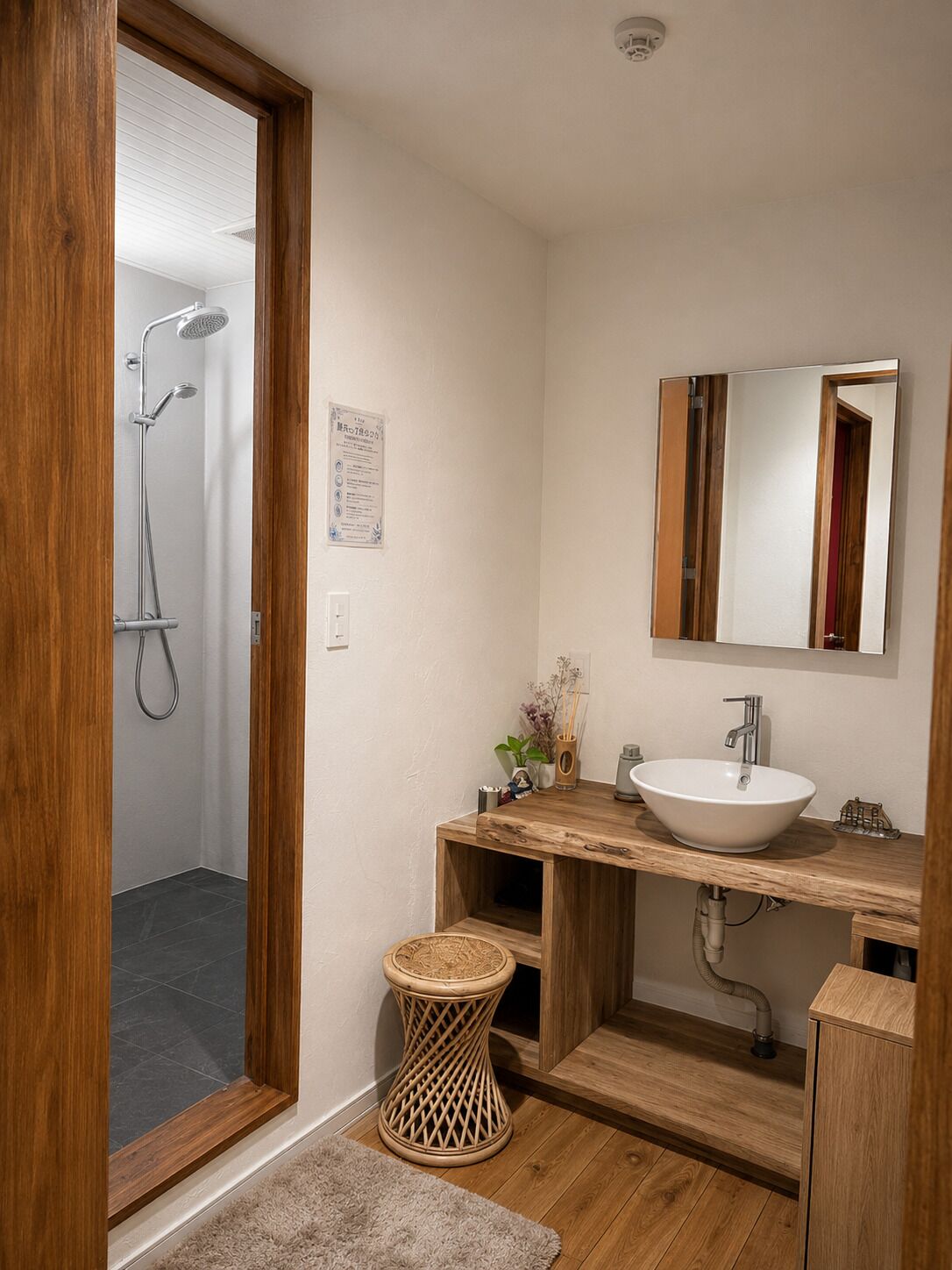 Un baño con tocador de madera, lavamanos blanco, espejo y ducha.