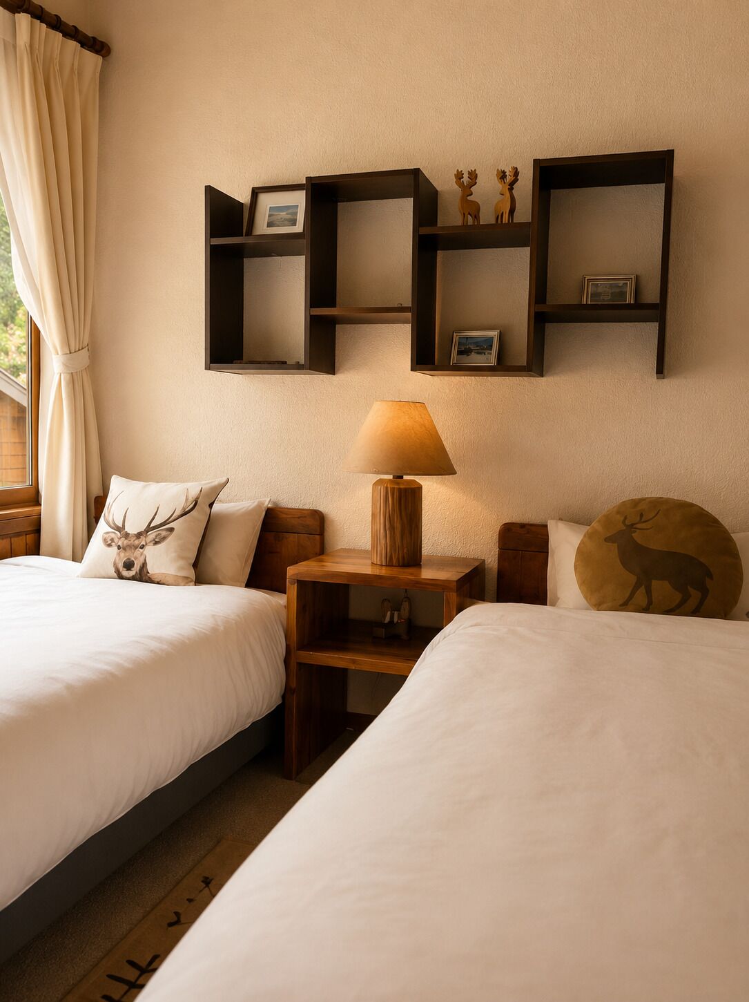 A hotel room with two beds, a nightstand with a lamp, and wall-mounted shelves with decorative items.