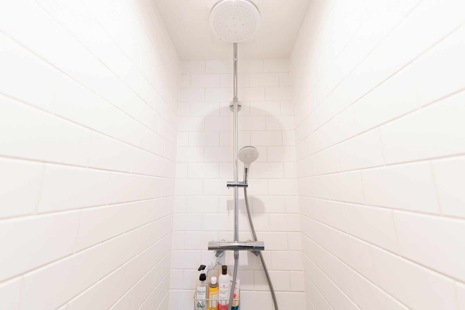 Een douche met een handdouche en een kraan op de muur.