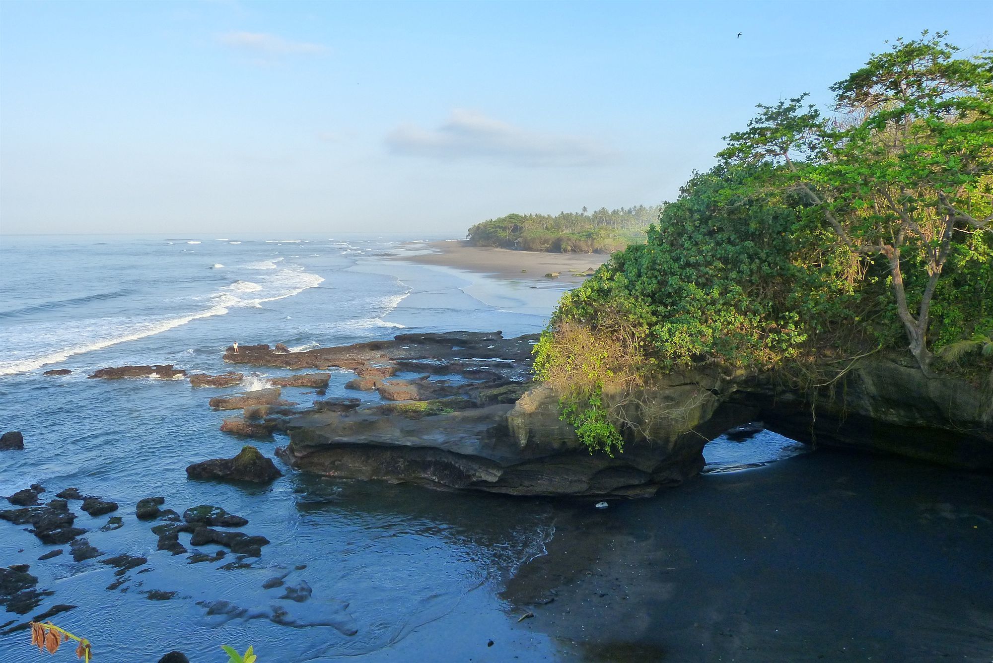 A coastal landscape with a rocky outcrop and a beach.