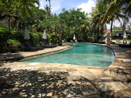 Una piscina al aire libre, sombrillas, sillones reclinables de piscina