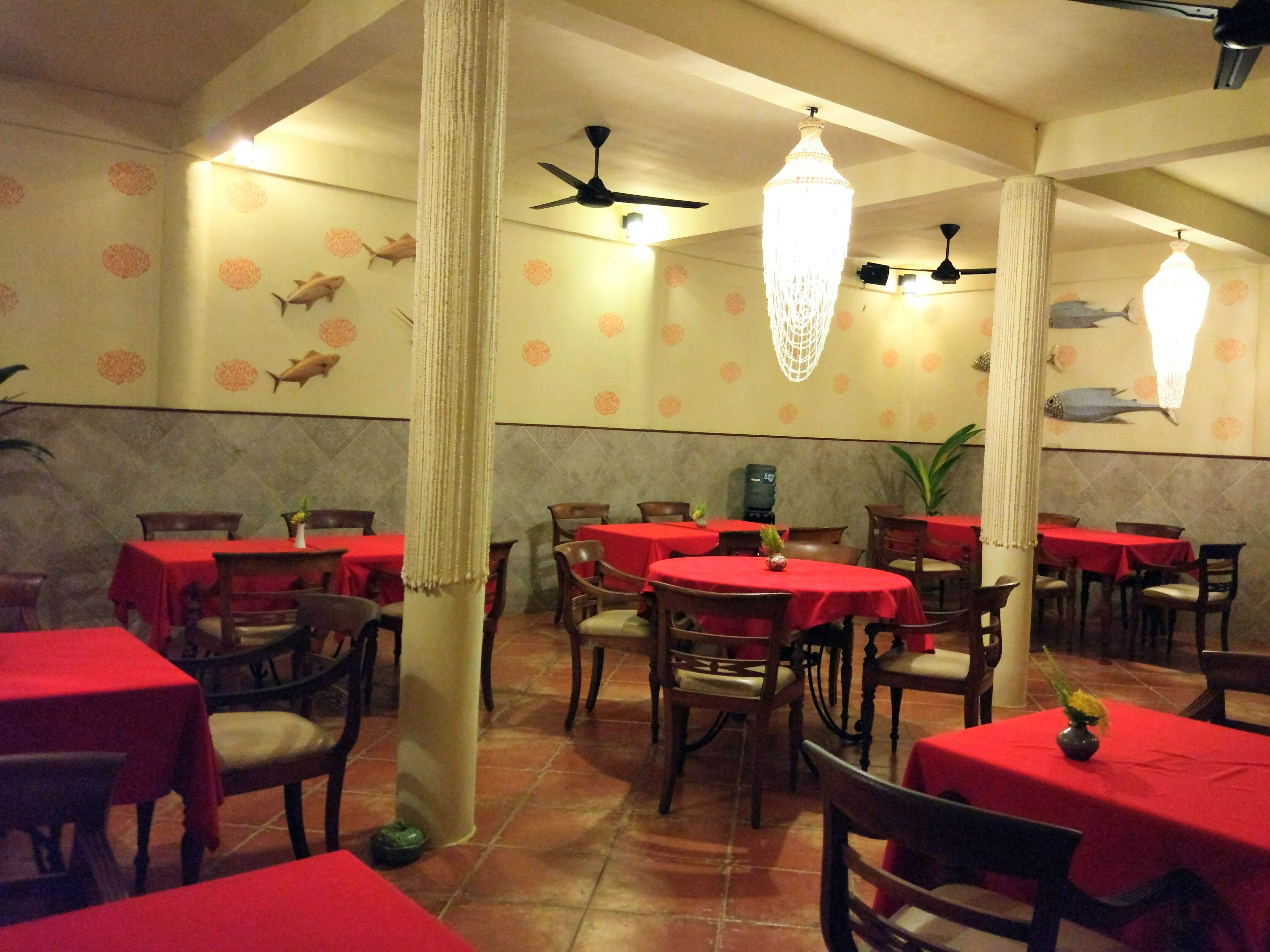 A restaurant interior with red tablecloths, wooden chairs, and decorative fish wall art.