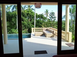 Un balcón con piscina, mobiliario exterior y exuberante vegetación.