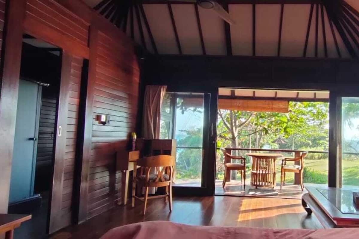 Ein Zimmer mit Holzvertäfelung, einem Esstisch mit Stühlen und Blick auf Grünfläche.