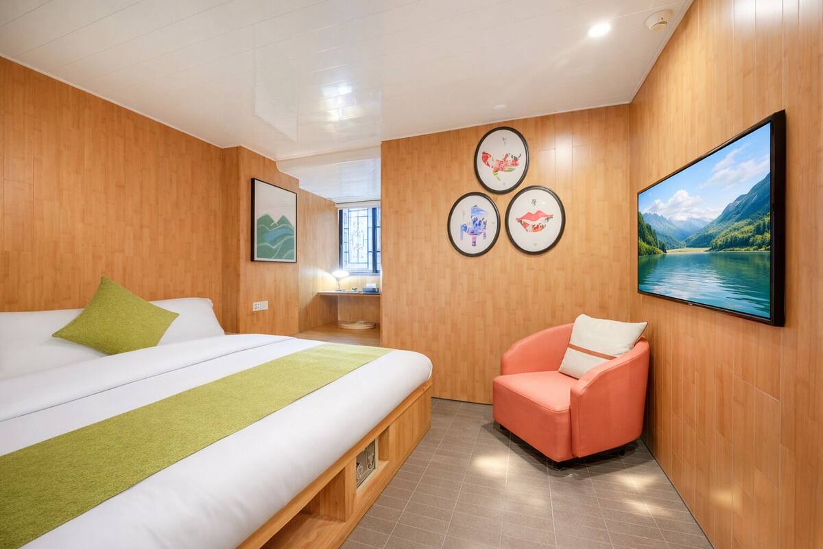A modern hotel room with a bed, a seating area, and artwork on the walls.