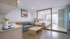 Una habitación de hotel moderna con sofá, cama, estación de café y vistas a la ciudad.