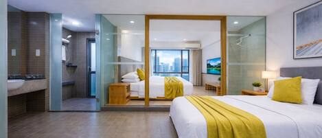 A modern hotel room with a large bed, a bathroom with a shower, and a city view.