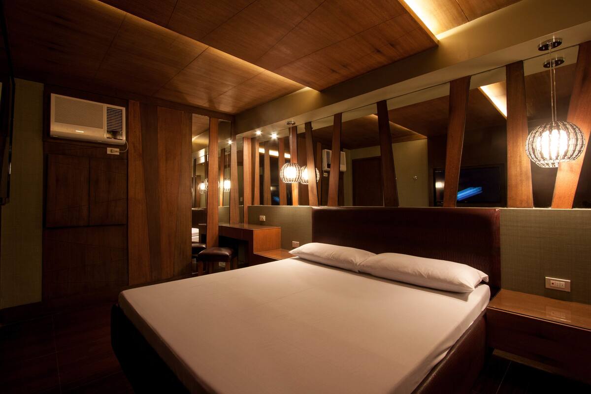 Una camera d'albergo con un letto grande, rivestimenti in legno, una scrivania e uno specchio.