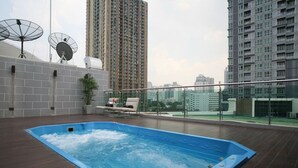 Une piscine sur le toit, avec une terrasse en bois, des chaises longues et des antennes paraboliques.