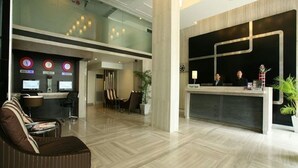 Un espace d’accueil moderne comprenant un comptoir de réception, un coin salon et une cloison en verre.