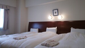 Camera d'albergo con due letti, una testiera, un quadro incorniciato e luci a parete.
