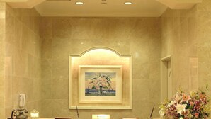 Una reception con un quadro incorniciato sopra, una piccola lampada da scrivania e un bouquet di fiori a destra.