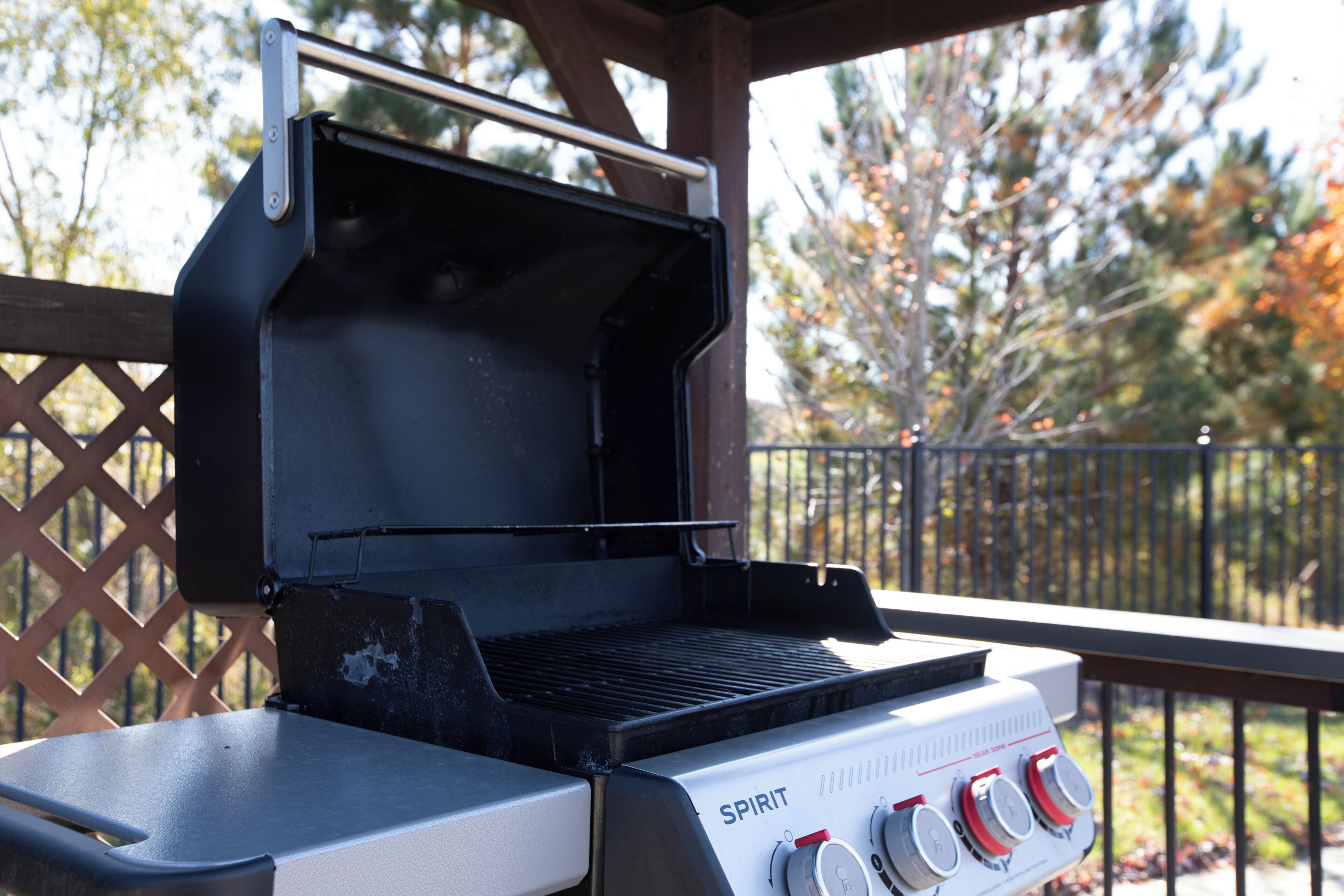 Un barbecue doté d’un panneau de commande, d’une grille en métal et, en arrière-plan, d’une clôture en bois.