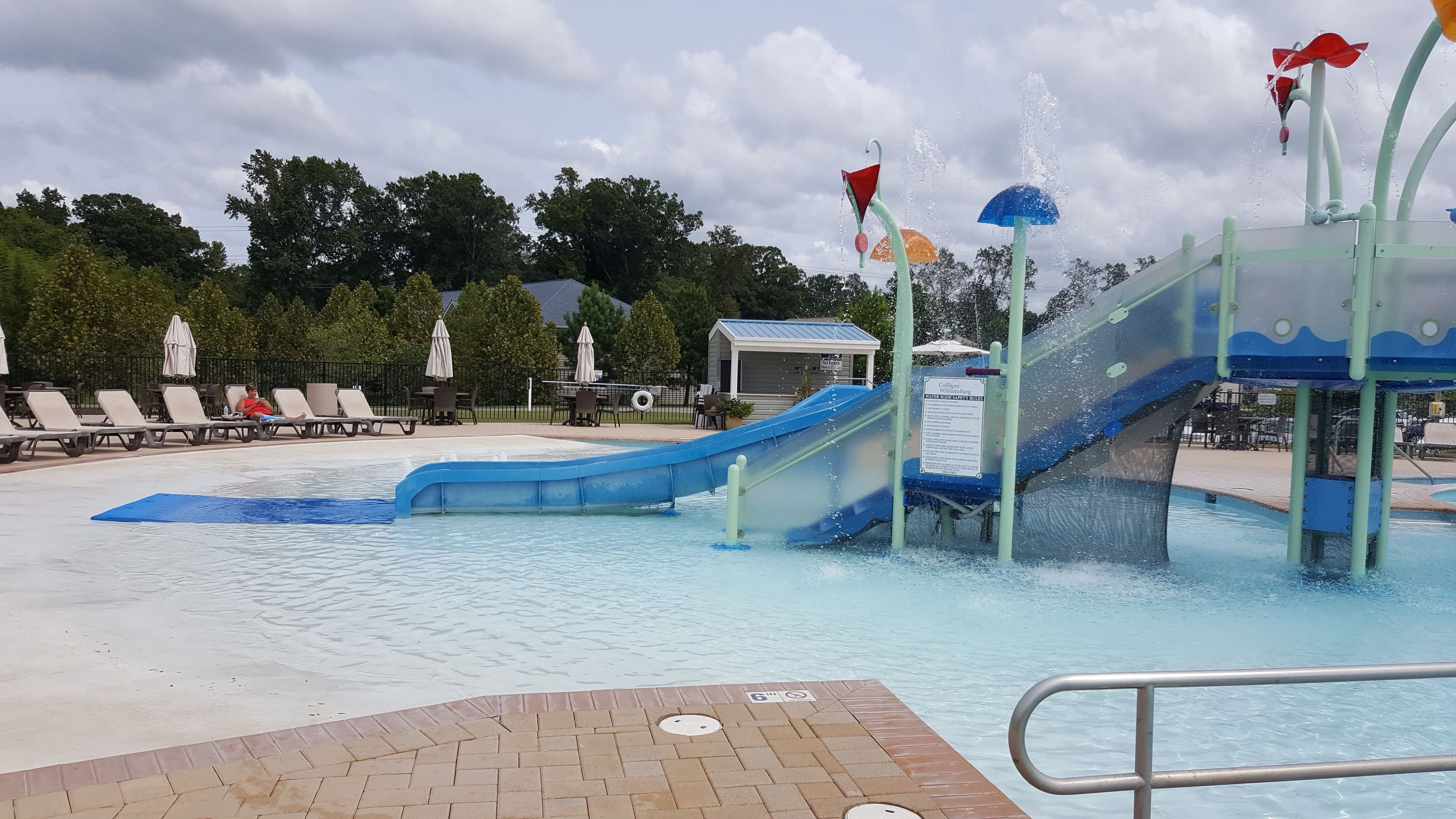 A water park with a blue water slide, lounge chairs, and a pool area.