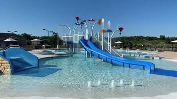 A water park with a blue slide, multiple water features, and clear blue skies.