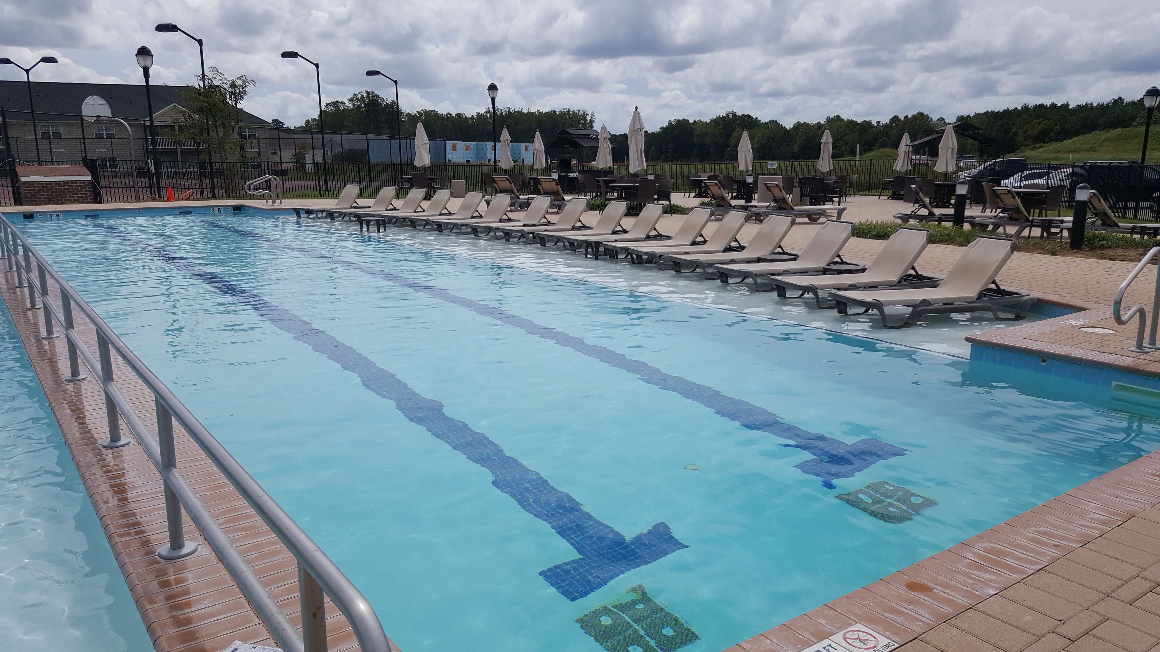 A swimming pool with multiple lanes, sun loungers, and umbrellas.