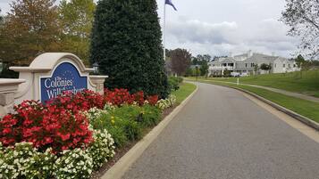 Señal de 'The Colonies at Willamette', con entrada ajardinada y una carretera que conduce a una zona residencial.