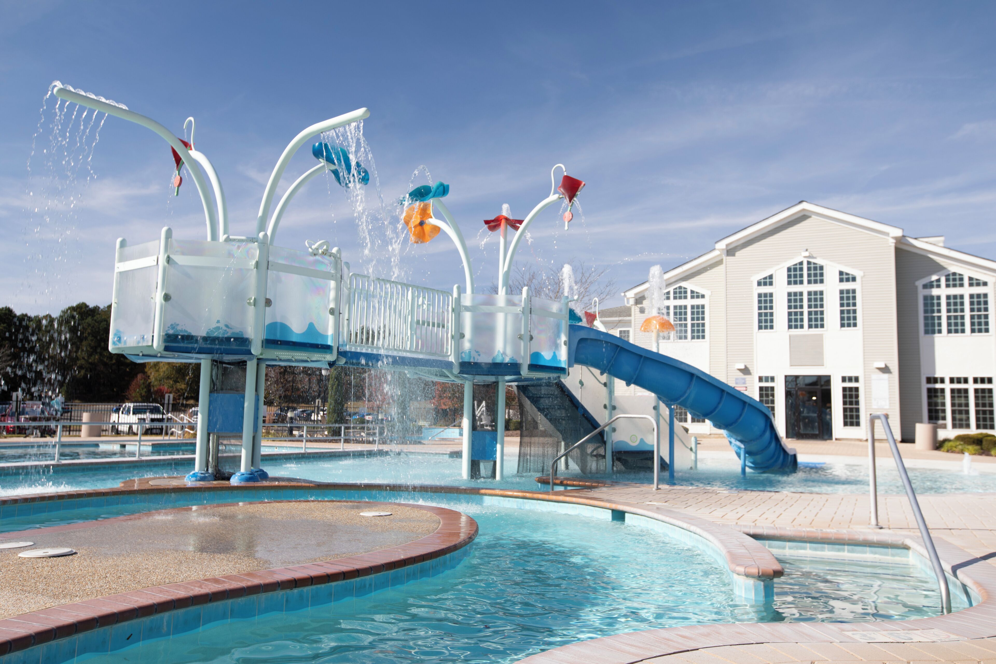 Ein Wasserpark mit Pool, Rutschen und einem Gebäude im Hintergrund.