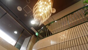Um interior moderno com uma luminária pendente decorativa, corrimão de metal verde e parede texturizada.