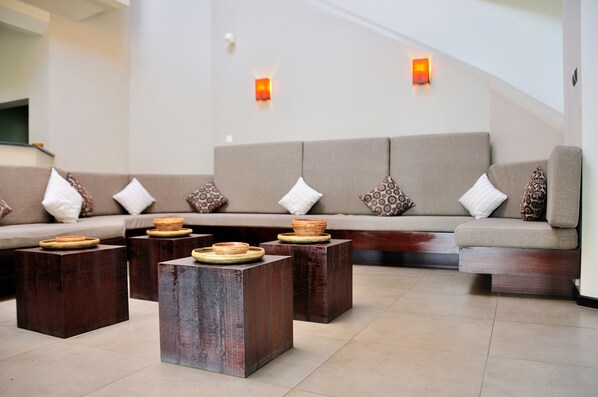 Un área de estar moderna con un conjunto de sofás, mesitas de madera y cuencos decorativos.