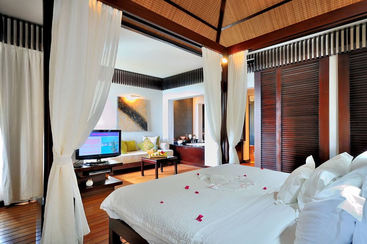 A spacious hotel room with a large bed, a television, a desk with a computer, and a view of the outside.