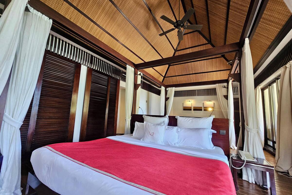 A spacious bedroom with a large bed, a ceiling fan, and a phone on a bedside table.