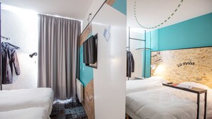 Habitación de hotel con dos camas, televisión, cabecera de madera y ventana con cortinas.