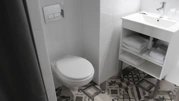 A bathroom with a toilet, a sink, and a shelf with folded towels.
