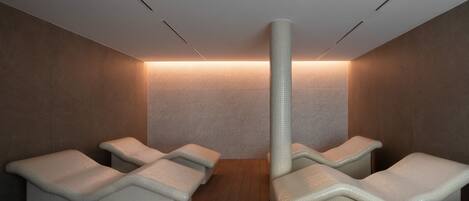 Un cuarto de spa con cuatro sillones reclinables, un muro con textura y una lámpara en el techo.