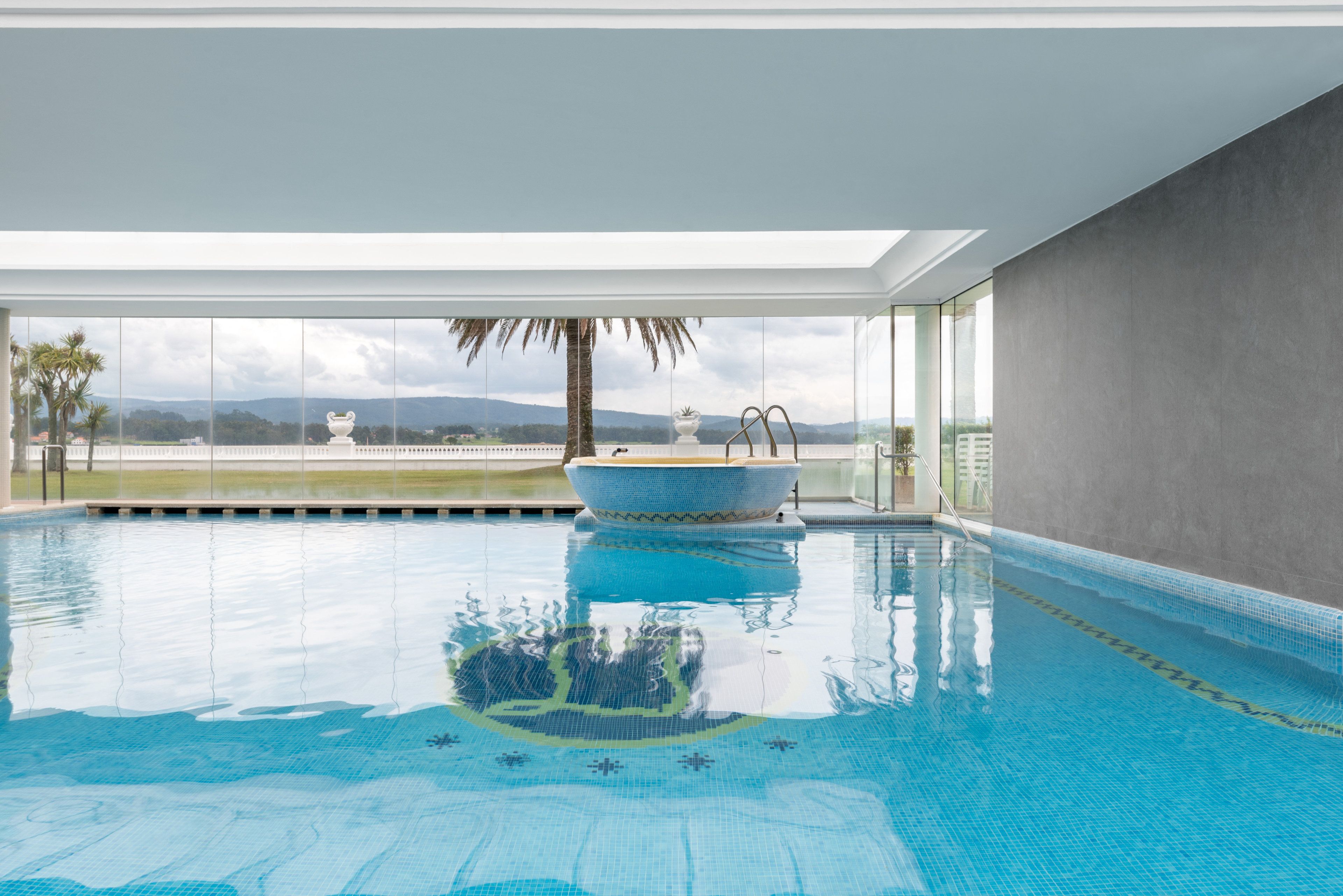 An indoor swimming pool with a clear view of the mountains in the background.
