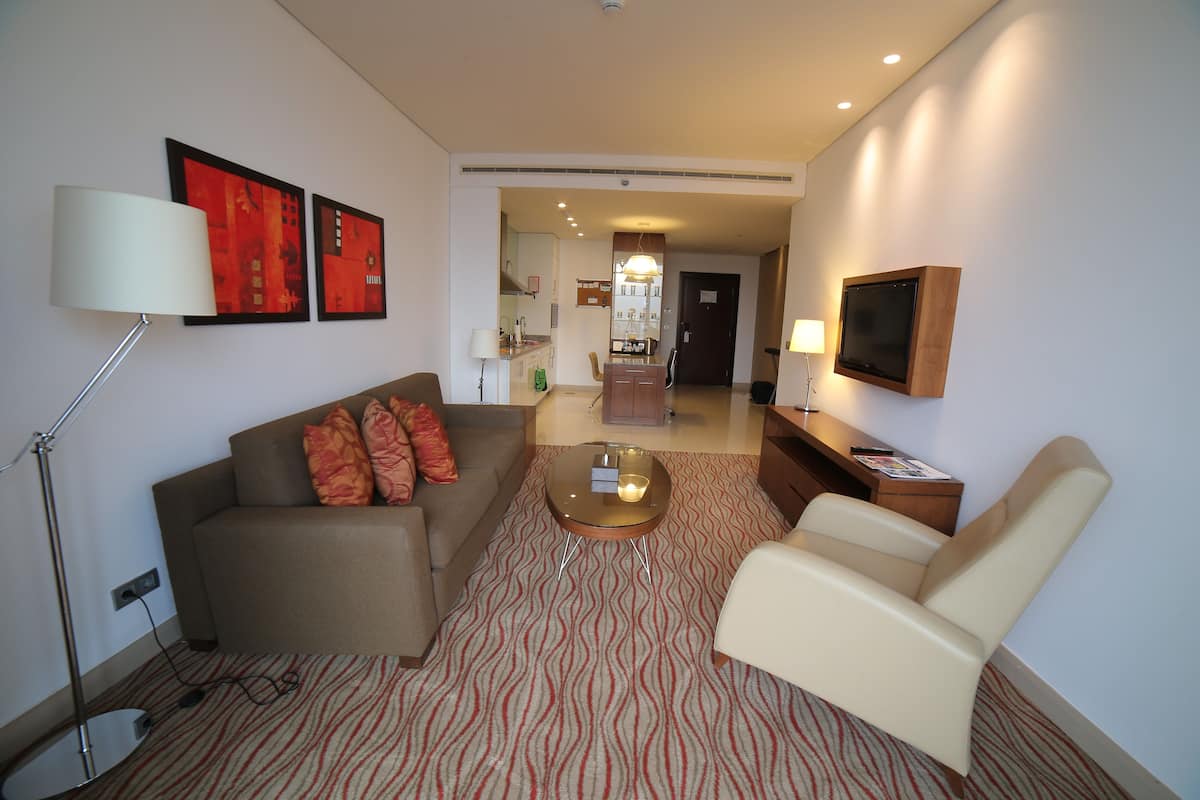 A modern living room with a sofa, armchair, coffee table, and artwork on the wall.